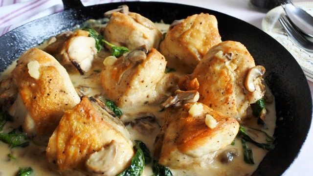 Creamy chicken with mushrooms and kangkong in a skillet.