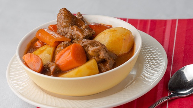 beef mechado with carrots and potatoes in a yellow bowl