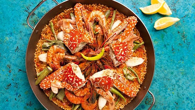 seafood sinigang paella topped with crabs, shrimp, sitaw, and white radish
