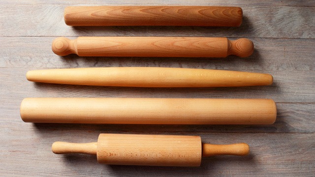 different rolling pins lined up on a wooden table