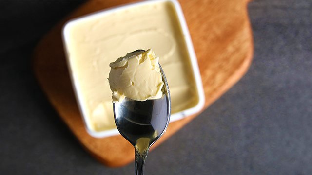 tablespoon scoop of butter with a ceramic bowl in the background