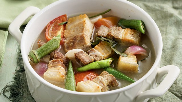 pork sinigang with green mangoes in a white ceramic pot