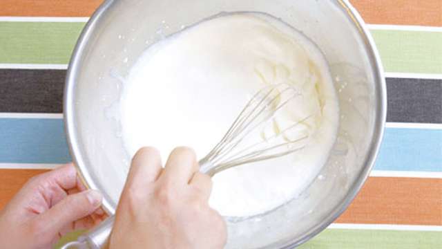 hands whipping cream in a stainless bowl