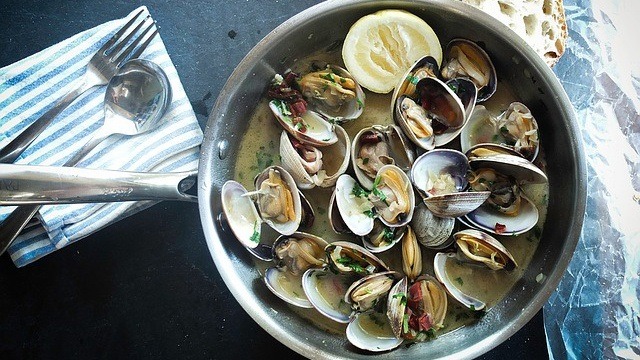 cooked clams in a sauce pan with lemons
