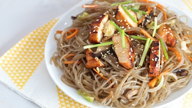 chapchae or japchae, korean glass noodles topped with roast chicken and greens