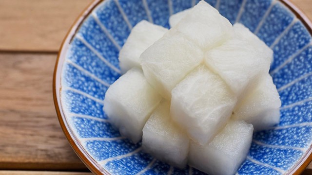 white cubed pickled radish or chicken mu in a small blue condiment dish