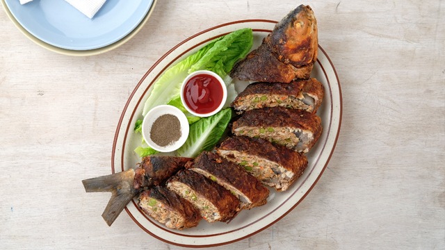 sliced rellenong bangus on a plate with ketchup and black pepper on the side