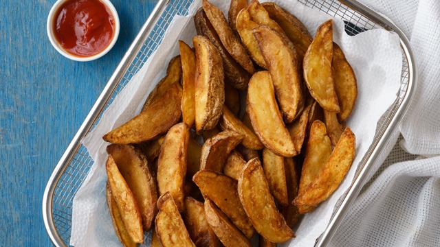 Fried potato wedges in a stainless basket