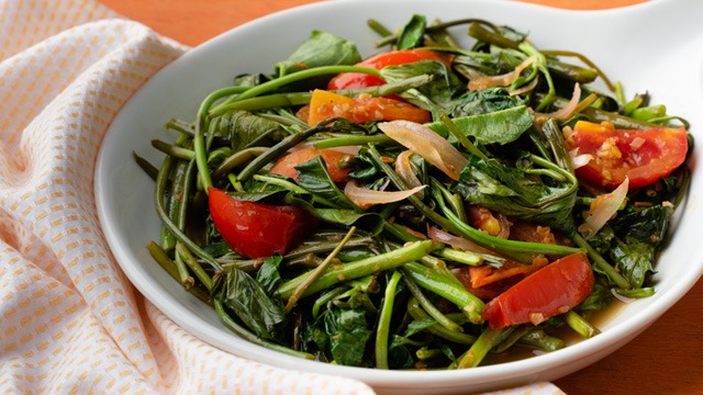 ginisang kangkong with tomato slices in a white bowl