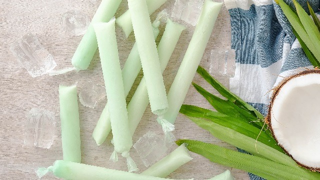 Buko pandan ice candy with coconut and pandan on the side