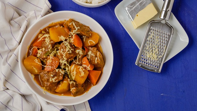 cheesy beef caldereta in a white serving plate