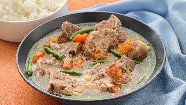 Pork ribs in broth with tomatoes in a gray bowl