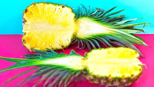 pineapples sliced in half on a turquoise and pink backgrorund