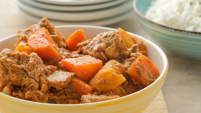 pork kaldereta with peanut butter, carrots and potatoes in a yellow bowl