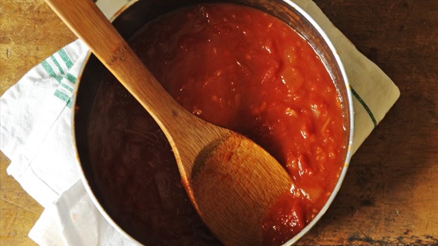 marinara sauce in a stainless steel pot with a wooden spoon in it