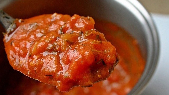 tomato puree being scooped out of a pot