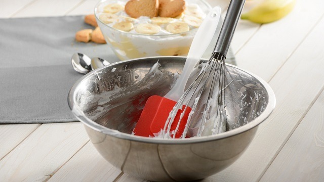 dirty rubber scraper or rubber spatula and whisk in a dtainless steel bowl