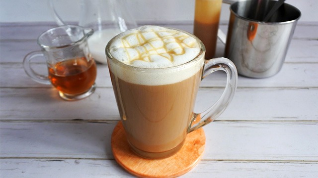 starbucks macchiato copycat in a clear mug on a wooden table with the ingredients behind it