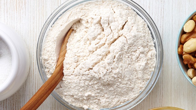 flour in a glass bowl with a wooden spoon in it