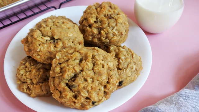 oatmeal cookies on a plate with milk and cooling rack against pink background