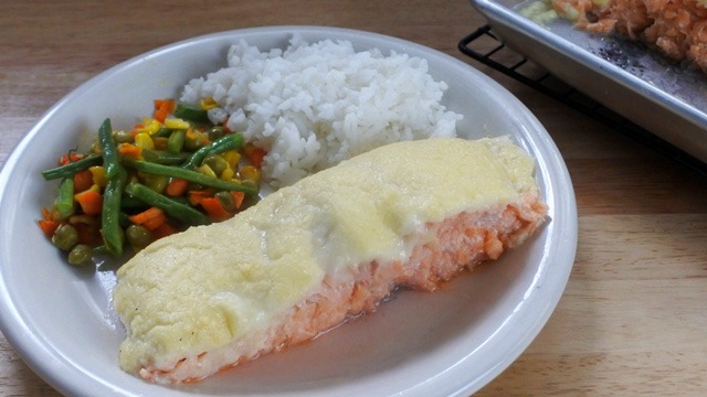 baked salmon ala conti's served with rice and buttered veggies on a white plate