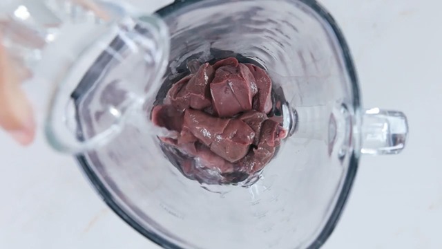 pouring water with fresh liver in a blender