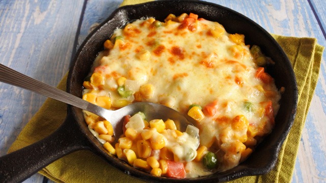 corn cheese in cast iron pan with spoon