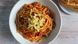pinoy cheesy spaghetti with hot dogs in a bowl