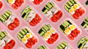 flat lay chicken breast and vegetables on a pink background