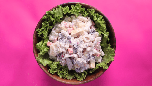 chicken macaroni salad on a bed of lettuce in a wooden bowl