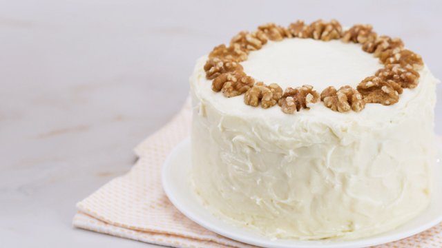 carrot cake decorated with cream cheese frosting and walnuts